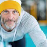 48787023-meia-idade-homem-dentro-casual-roupa-de-esporte-e-gorro-sorridente-exercicio-em-esteira-dentro-moderno-academia-com-turquesa-pavimentos-e-ginastica-equipamento-foto